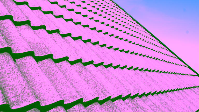 Närbild på ett rent, grått tegeltak under en klarblå himmel, ett utmärkt exempel på resultatet av Nanostones professionella takbehandling. Våra erfarna metoder säkerställer att ditt tak blir fritt från påväxt och smuts, vilket skyddar och förlänger dess livslängd på ett säkert och effektivt sätt.